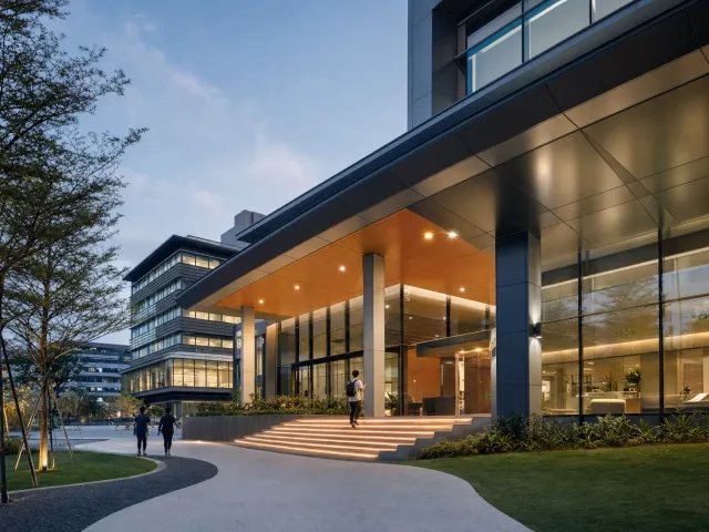 Campus building entrance at dusk with students walking up the lit steps